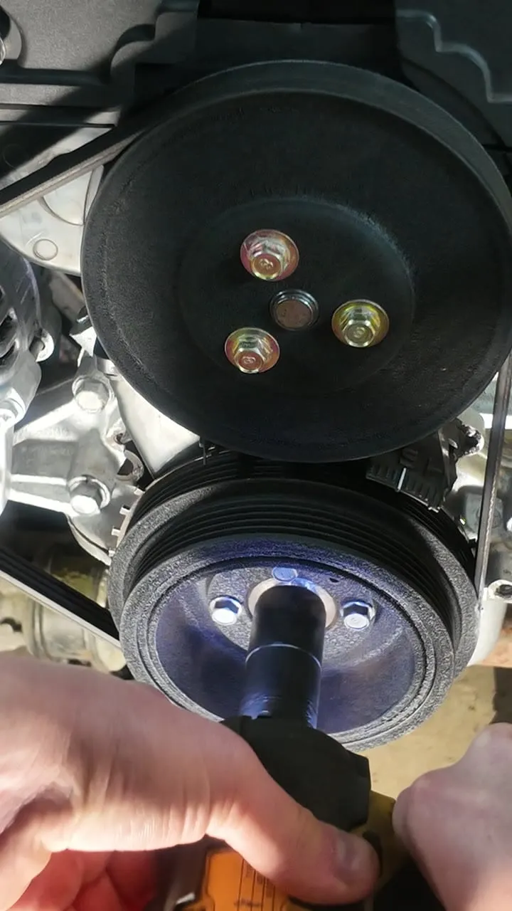A timing light strobe firing on the running engine's crank pulley