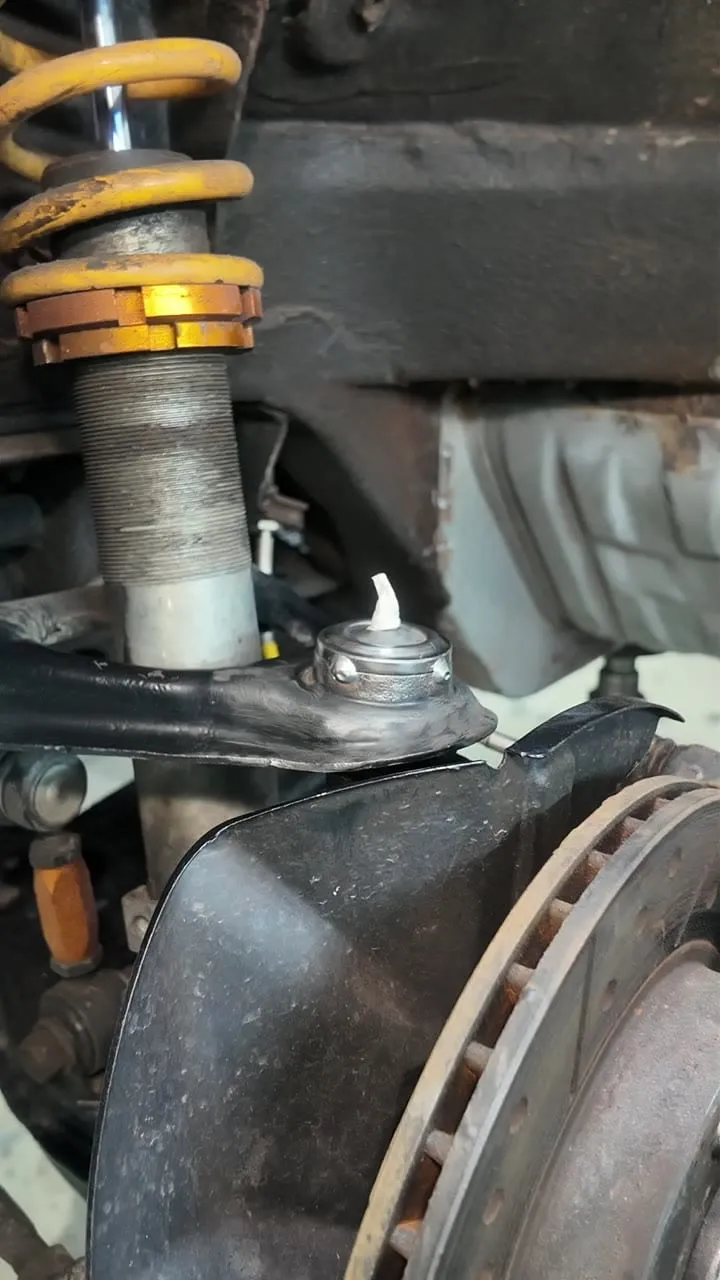 The MX-5 upper ball joint seated in the arm after tacking, the weld visible at the collar