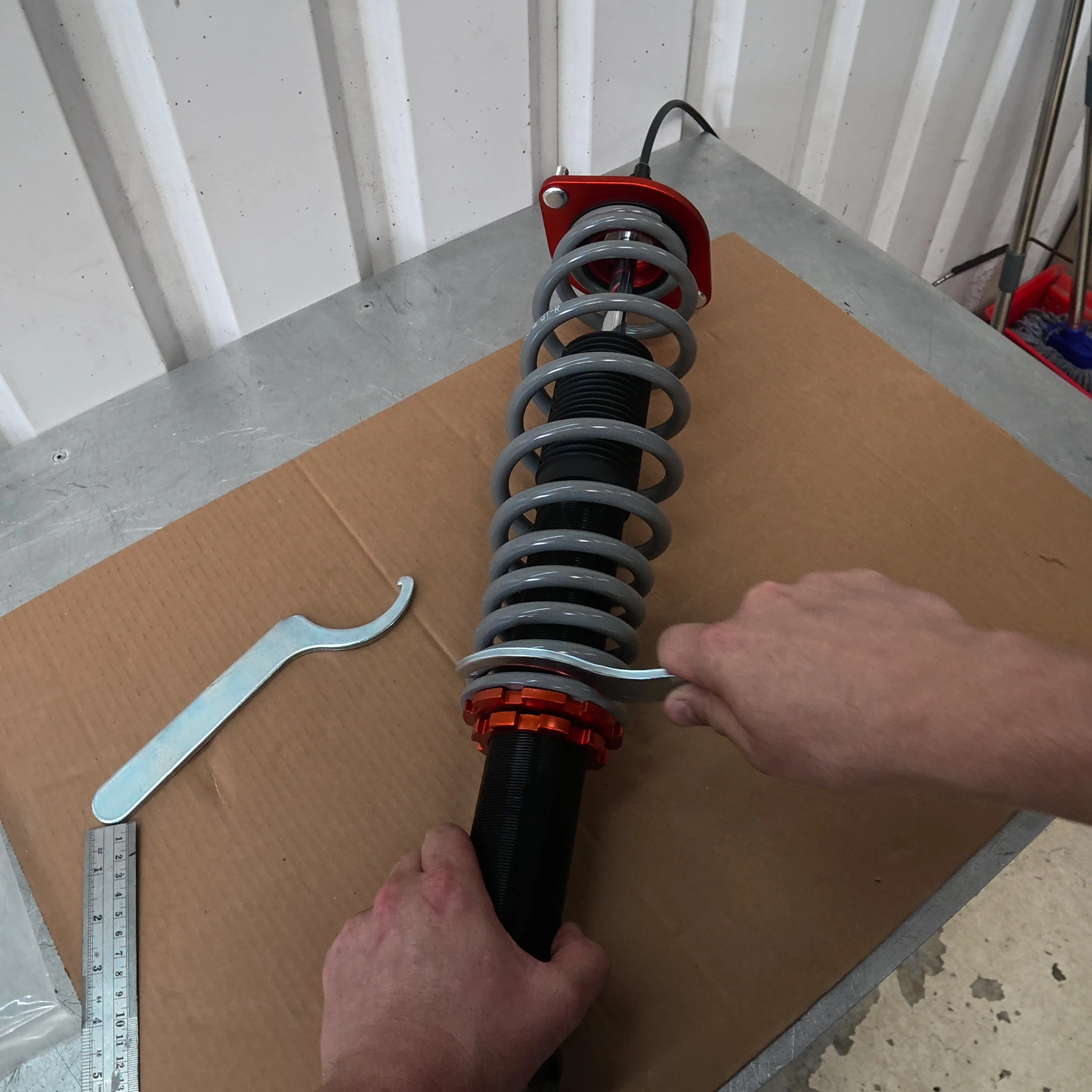 Measuring a rear Tecna on the bench with a steel rule, C spanner on the locking ring, remote adjuster cable fitted to the top mount