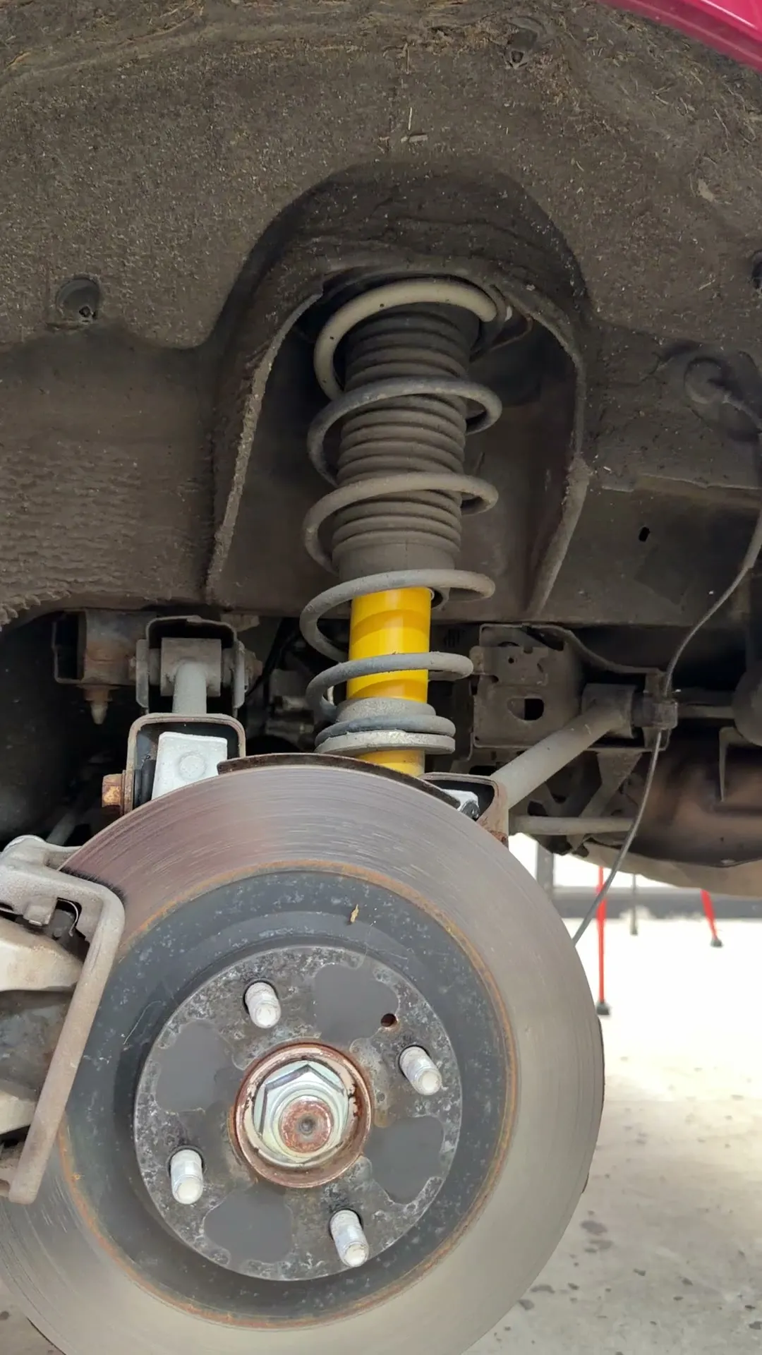The original yellow damper and spring in the rear arch before the job