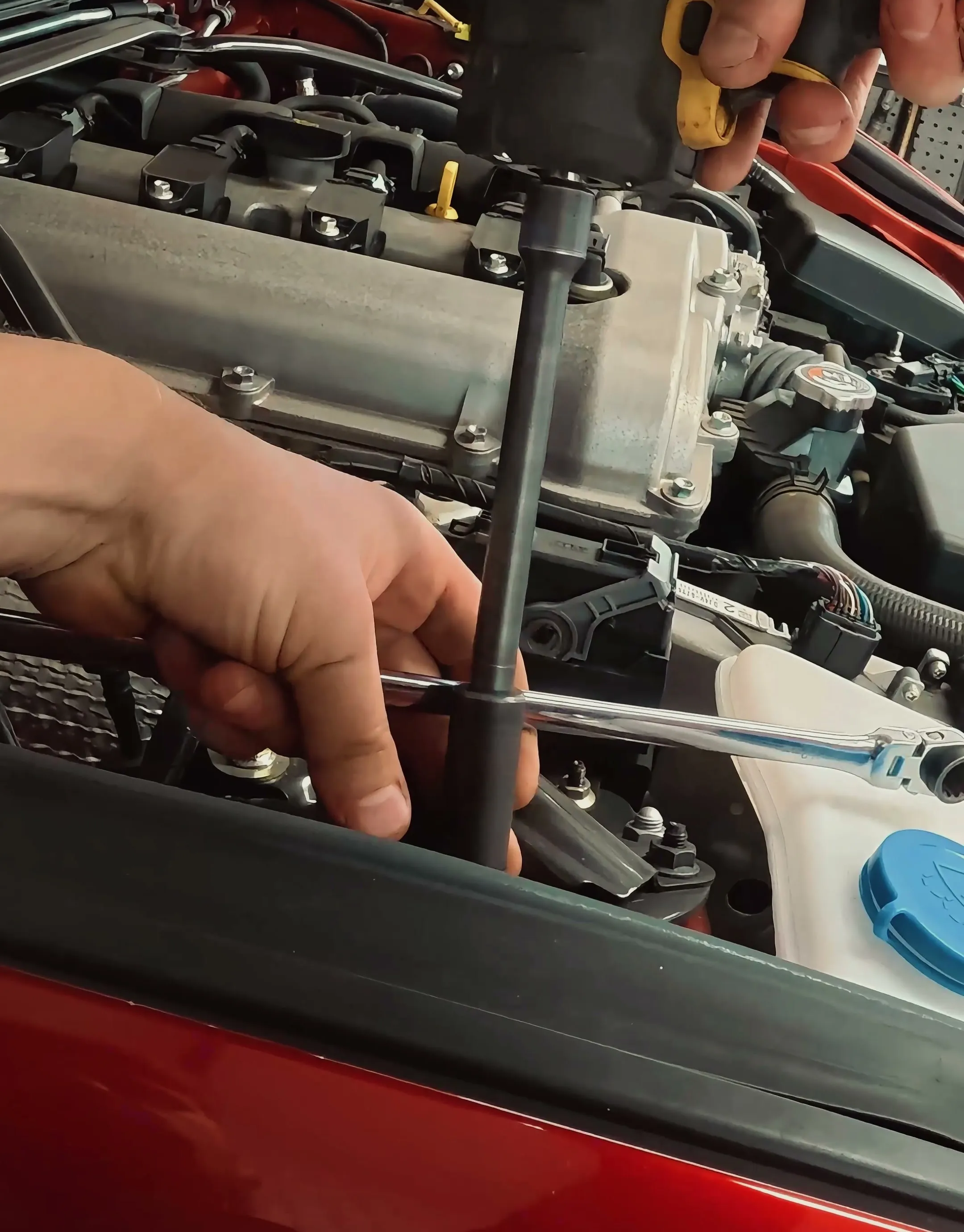 Ratchet and long extension reaching down to the front top mount nuts from the engine bay