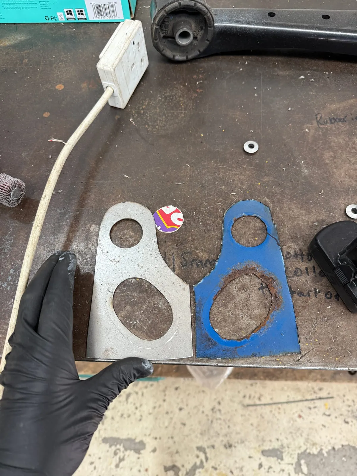 A corroded original bracket next to the new plate made to replace it