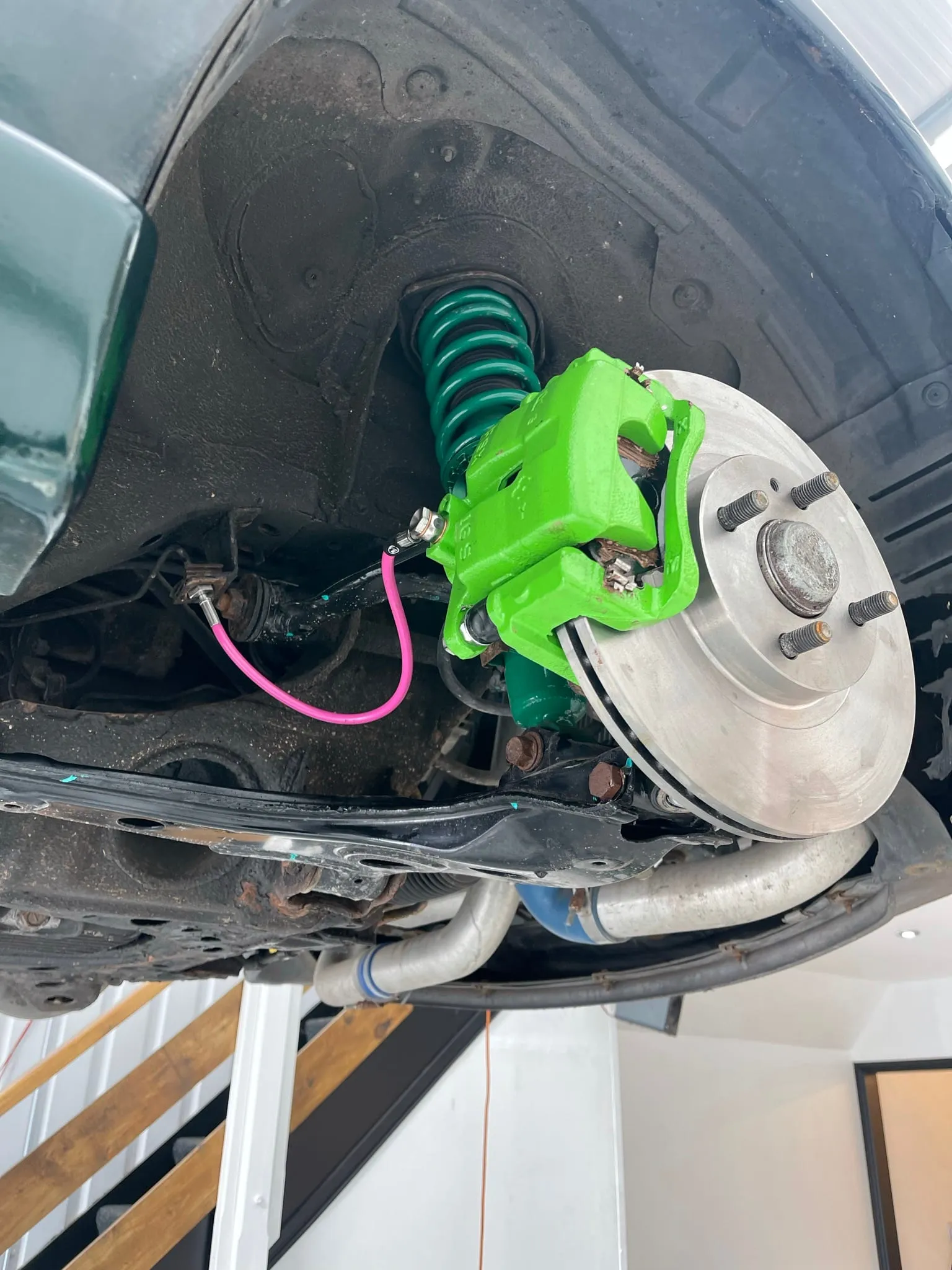 A freshly fitted green Wilwood caliper and drilled disc on an MX-5, wheel off