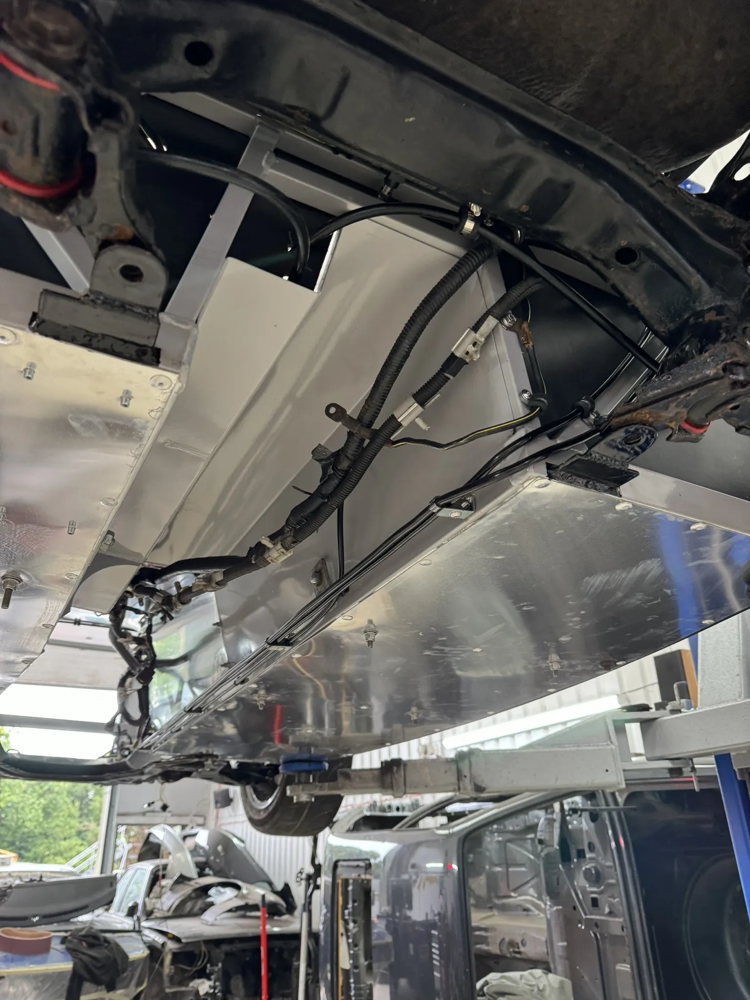 Under the car on the ramp, brake and fuel lines running along the floor panel