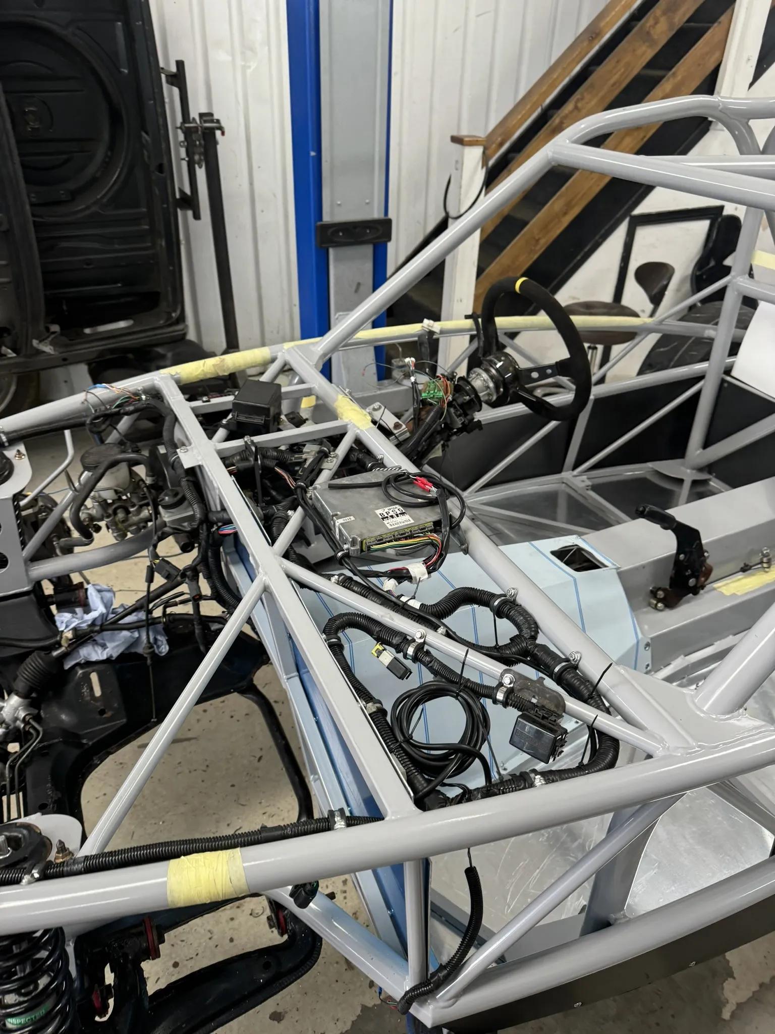 The loom along the top rail of the chassis, still in its old conduit, steering wheel behind