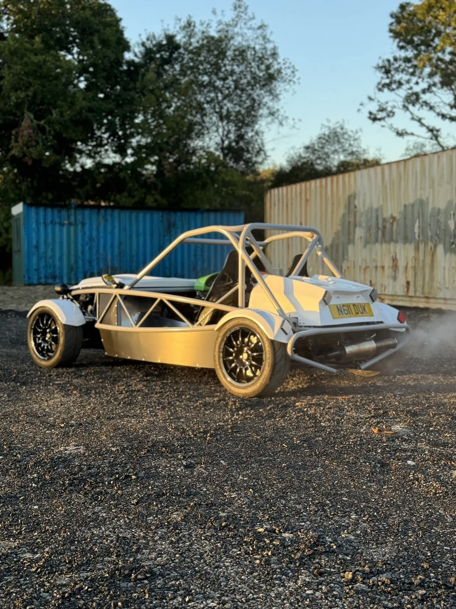 The finished car from the rear three quarter by the containers in low morning sun