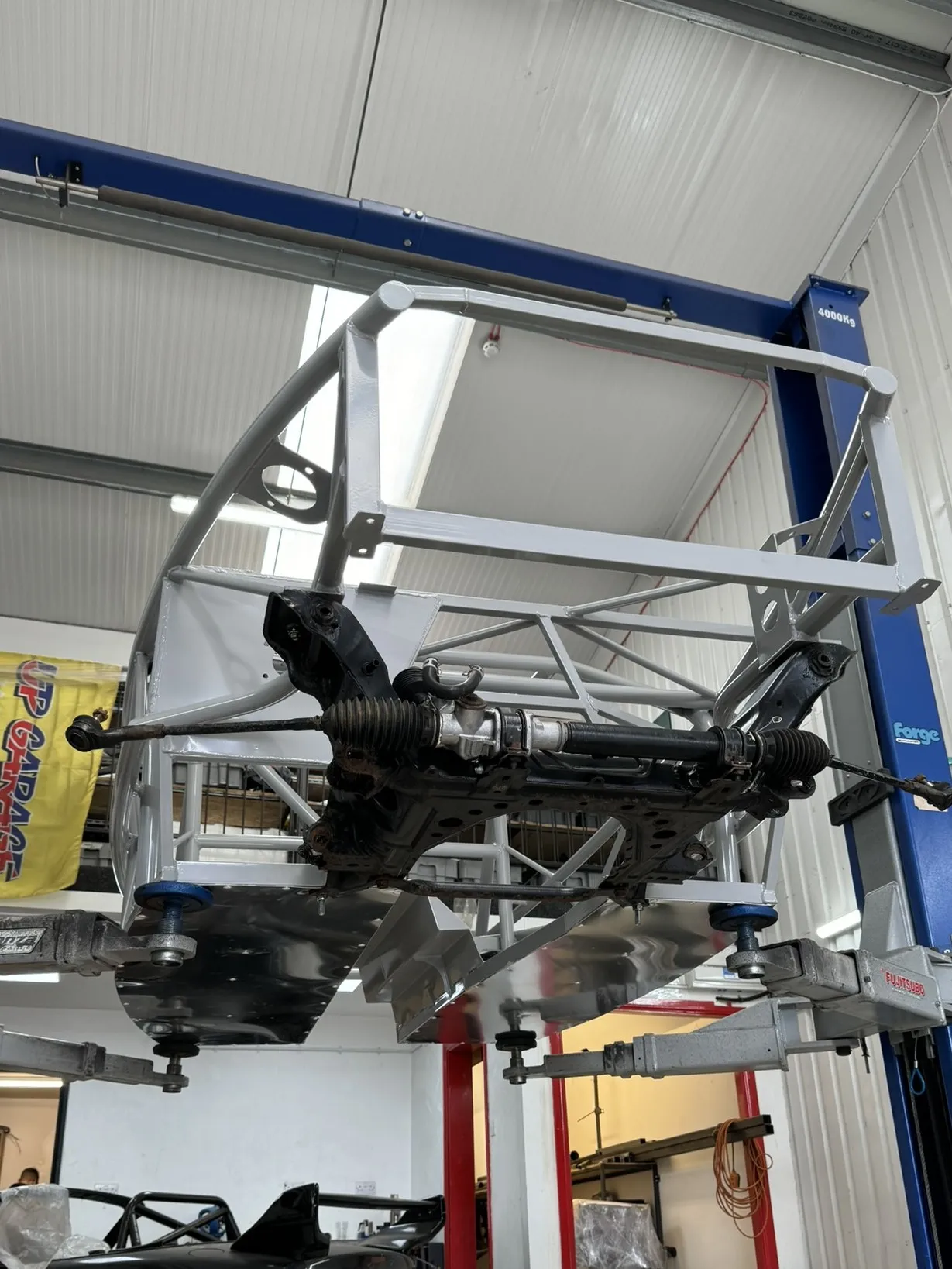 The front subframe and steering rack in, seen from underneath on the ramp, the rear subframe waiting on the floor