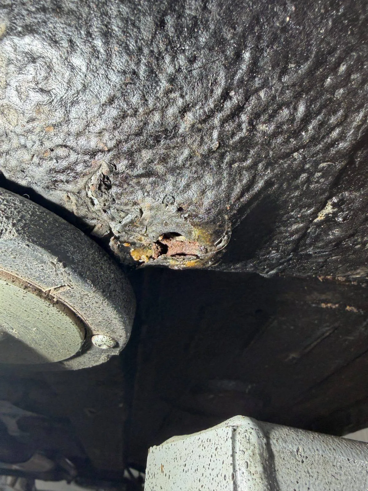 Bituminous undercoat lifting over the torque box, with corrosion underneath