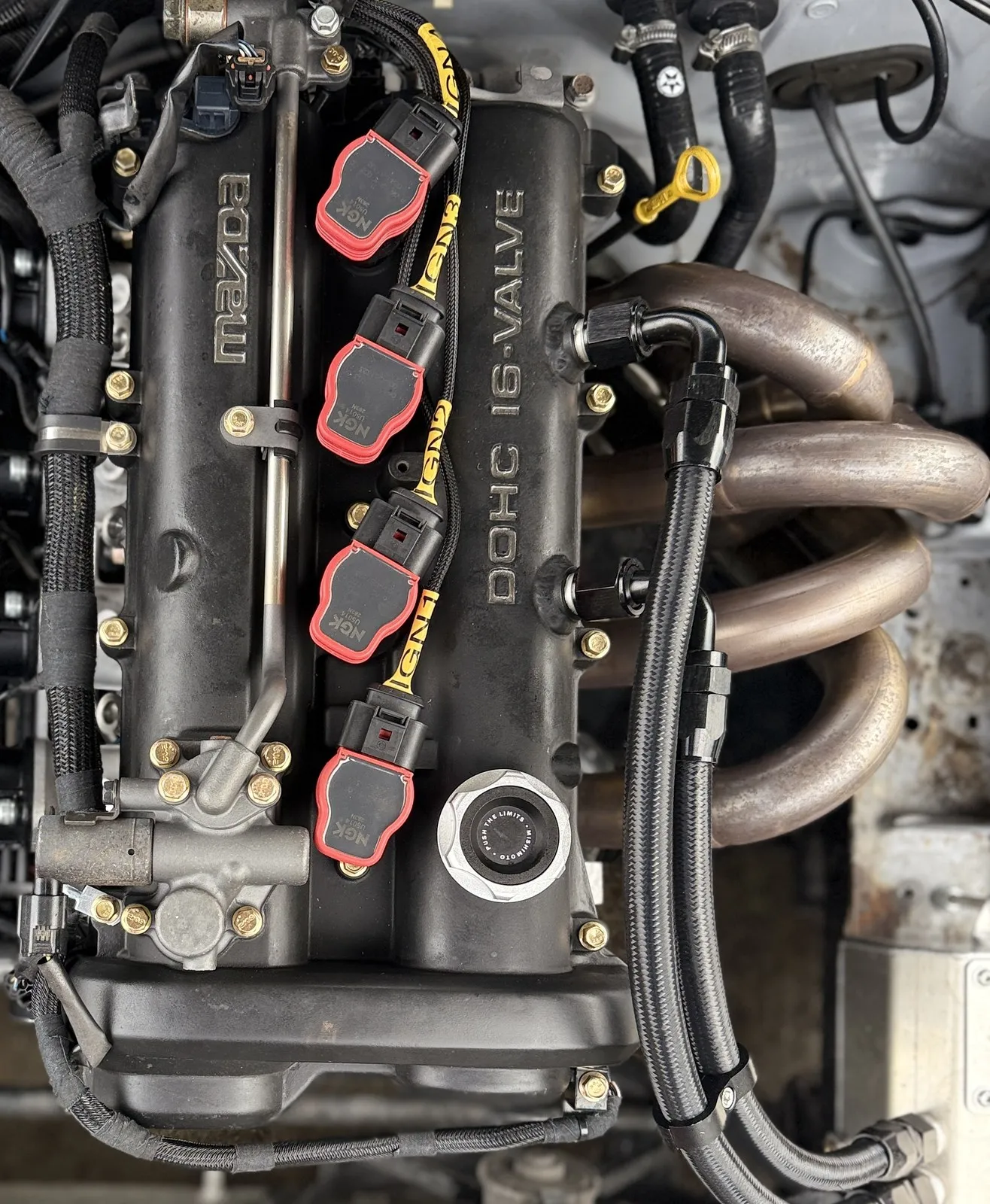 Top down view of the modified rocker cover, two braided AN lines teed off it and running to the catch can