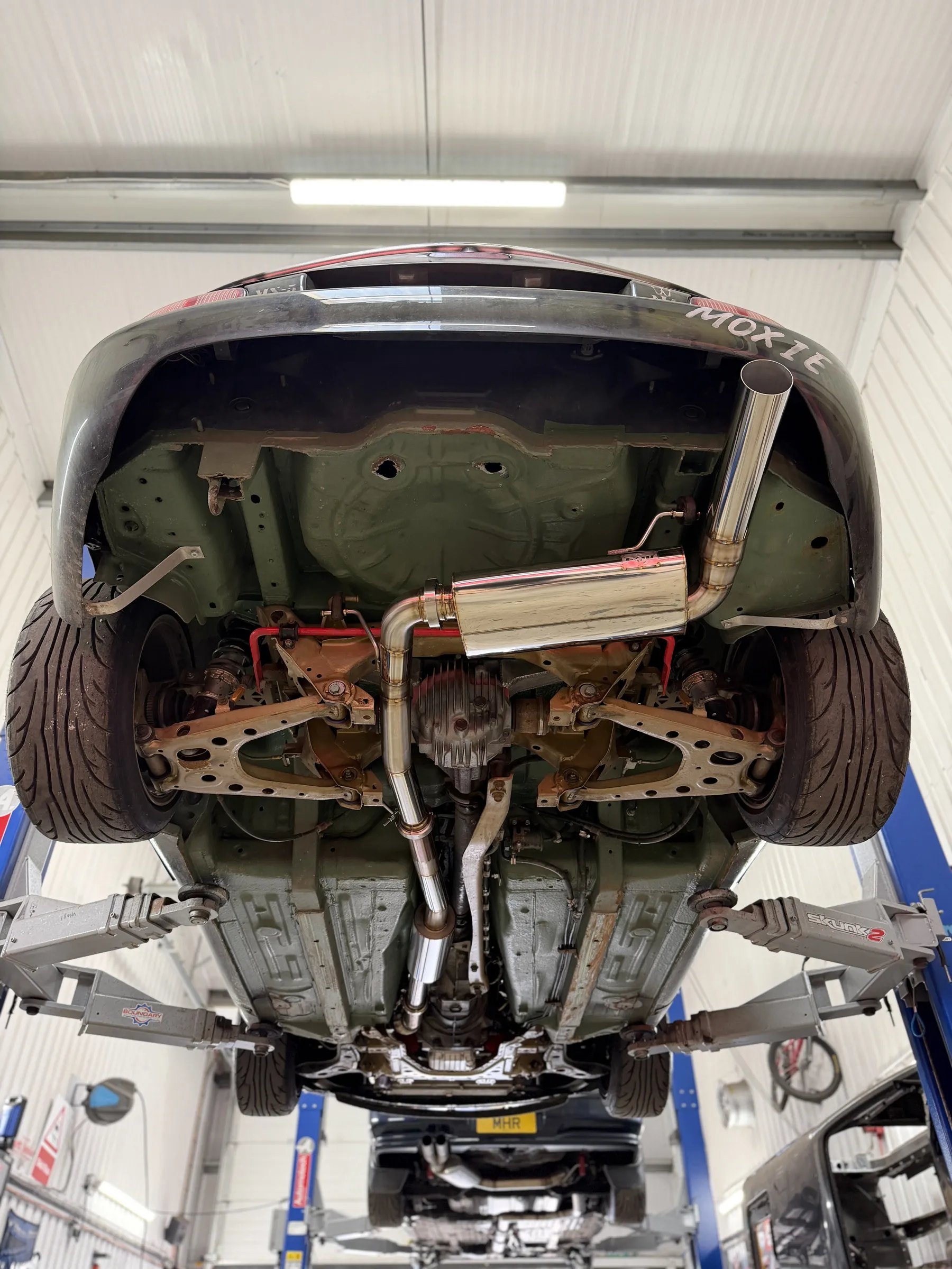 The finished stainless system seen from underneath the car on the ramp, running the length of the floor