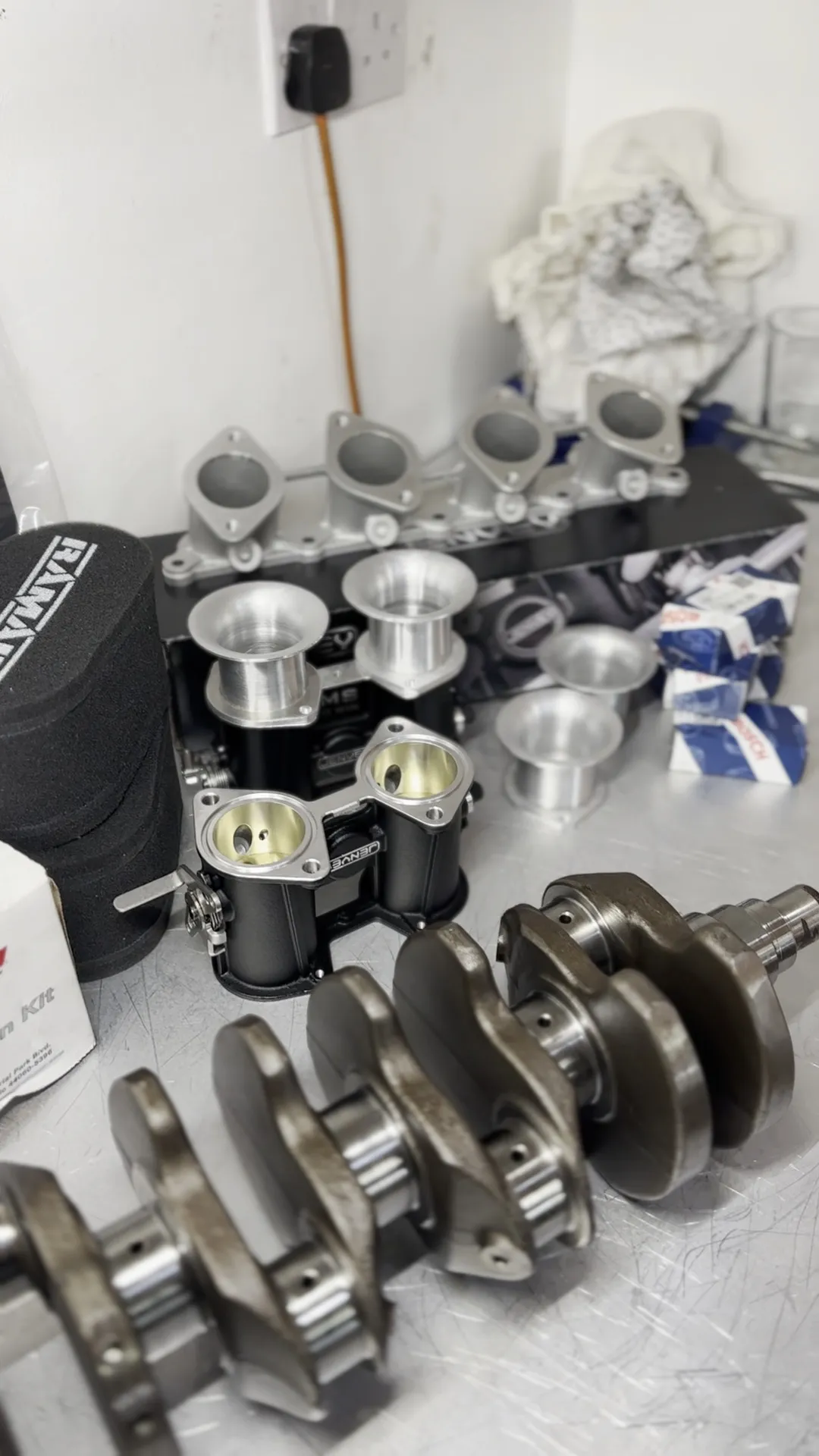 The parts laid out on the bench before assembly, the crank alongside the boxed Wiseco pistons and bearings