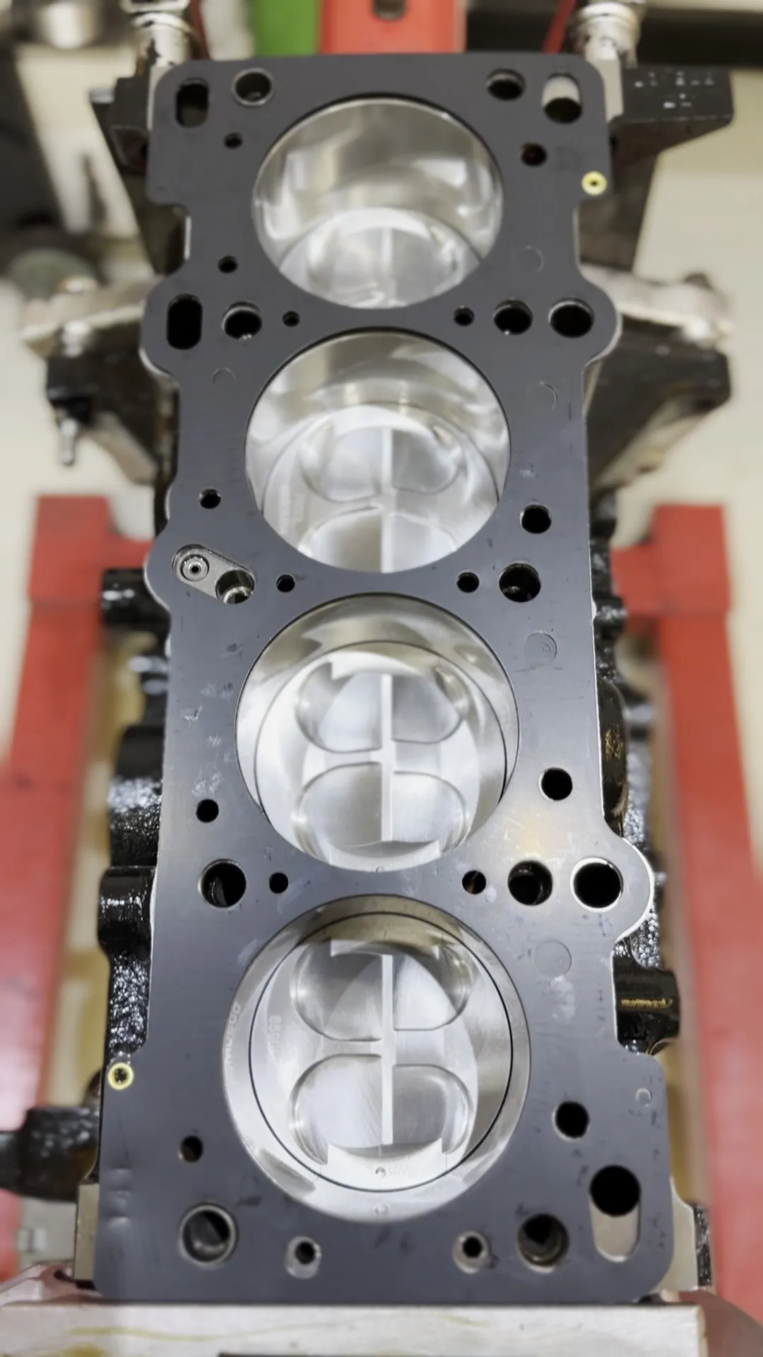 Looking down on the block deck with the forged pistons fitted, valve pockets visible in the crowns