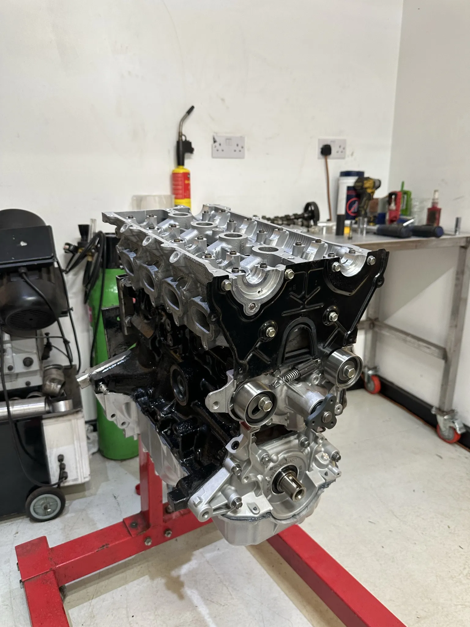 The engine roughly assembled on the stand, head on and timing gear fitted with no cam cover yet