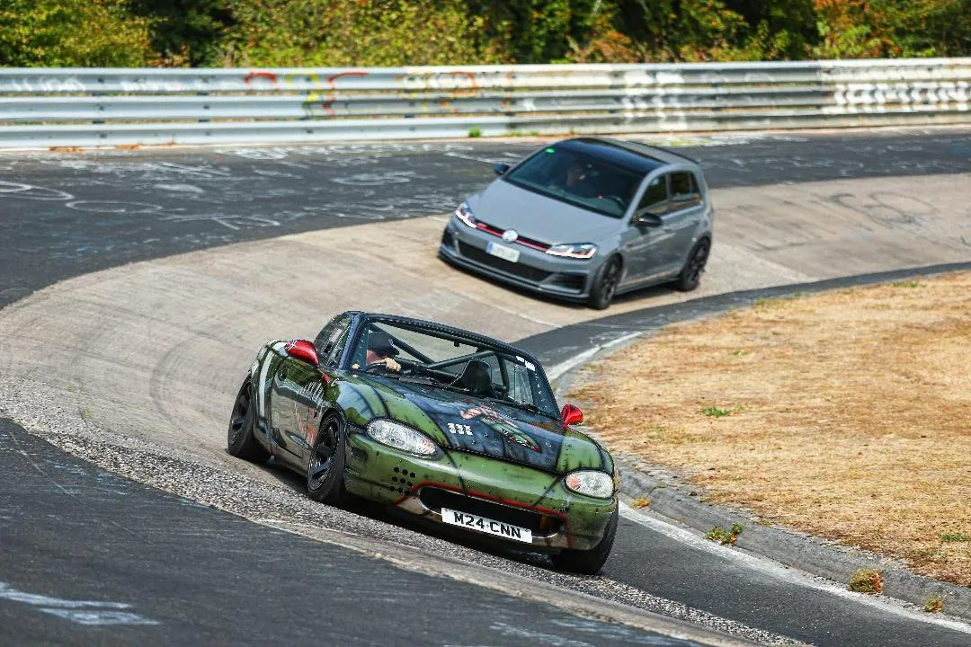 Mark's military green Mk2 MX-5 with shark mouth nose art on track at the Nürburgring, turning in ahead of a Golf GTI