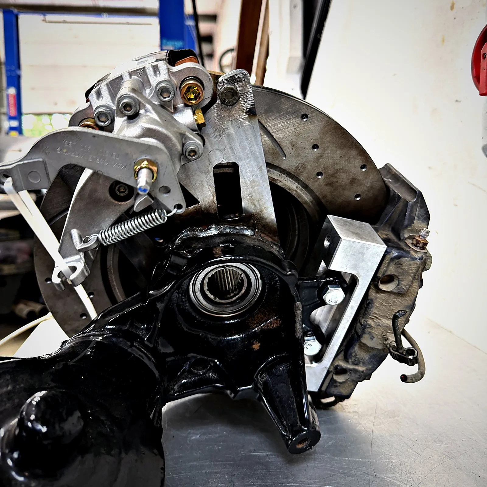 The back of the hub: the steel handbrake bracket welded on with the Wilwood caliper fitted, and the aluminium caliper block bolted to the trailing arm beside the Porsche caliper