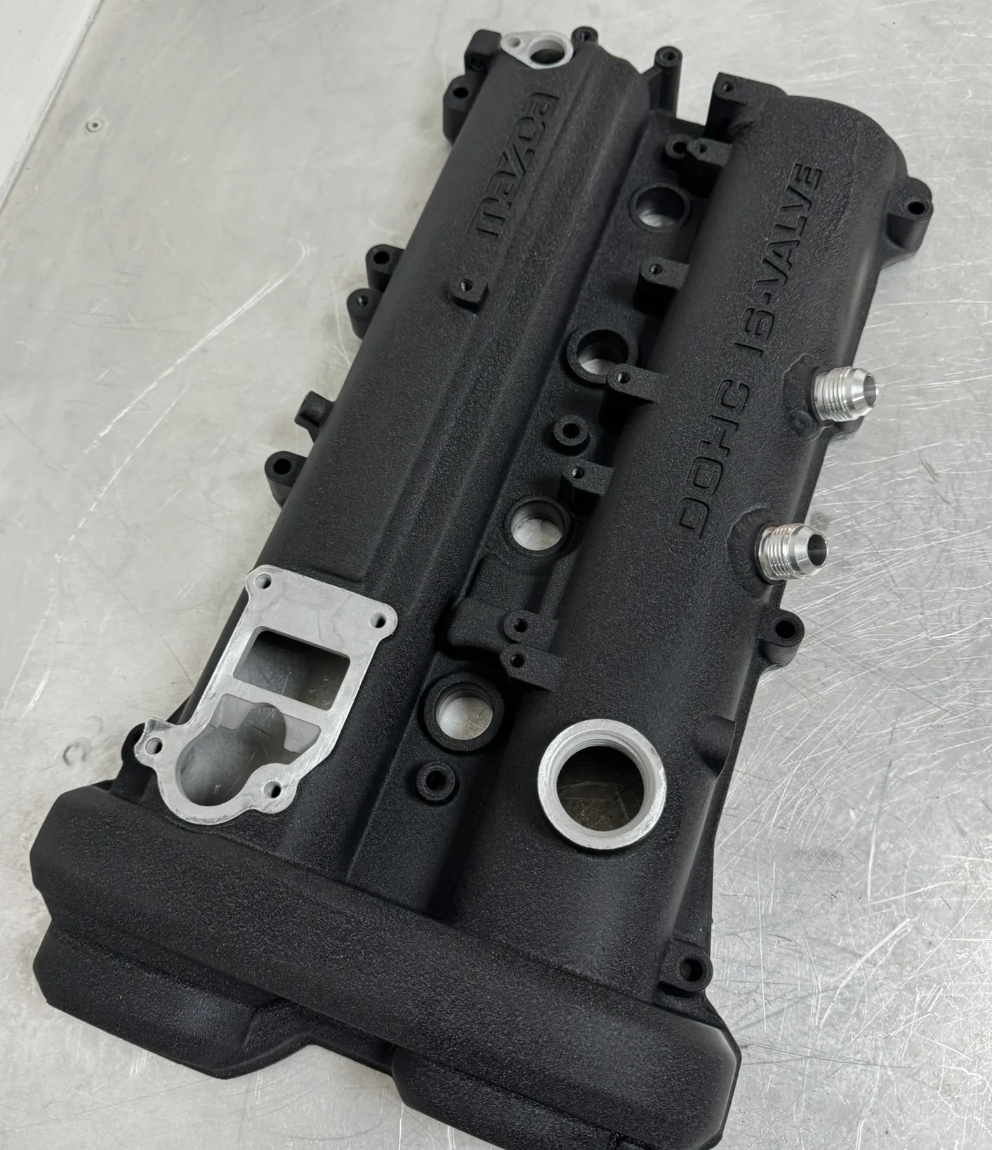 A finished FOJI baffled rocker cover in wrinkle black, the two AN10 fittings welded on at 45 degrees and the filler neck machined back